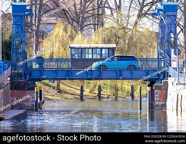 PRODUCTION - 28 March 2023, Mecklenburg-Western Pomerania, Plau am See: A car drives over the historic lift bridge over the Elde River