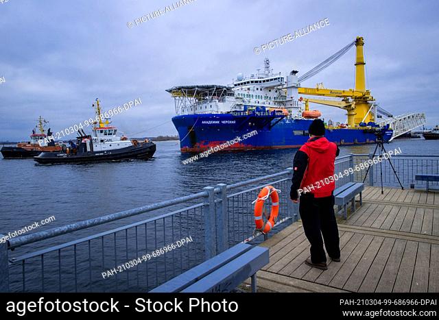 04 March 2021, Mecklenburg-Western Pomerania, Wismar: A man takes a photo from the pier of the Russian pipe-laying ship ""Akademik Tscherski""