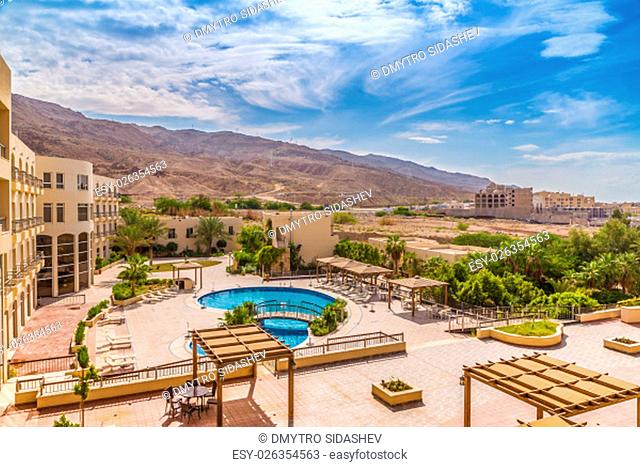 Hotel swimming pool with views of the desert mountains. Around the pool are growing tropical plants