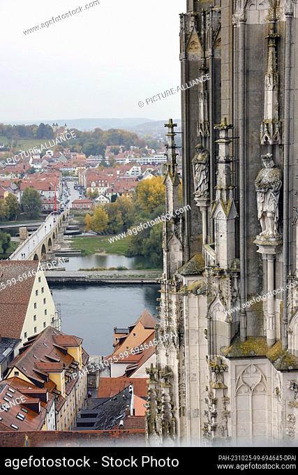 PRODUCTION - 24 October 2023, Bavaria, Regensburg: Sandstone figures covered with moss stand at a height of about 60 meters on a tower of the Regensburg...