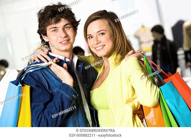 Portrait of loving couple after buying gifts looking at camera with smiles