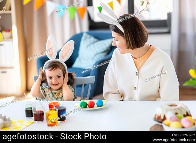 mother with child dyeing easter eggs at home