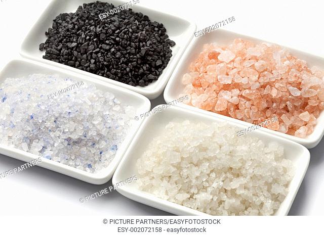 Four types of salt in white dishes close up