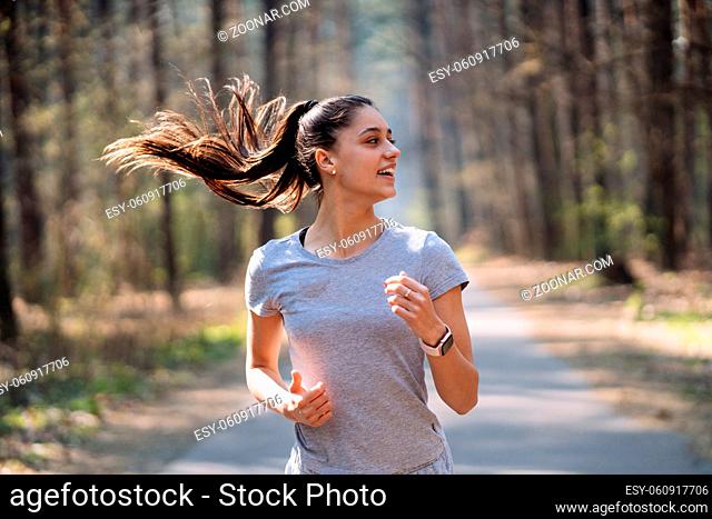 Beautiful young woman running in green park