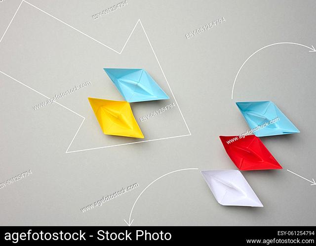 Two groups of paper boats stand opposite. Yellow-blue forces a group of ships to retreat. View from above