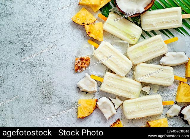 Homemade pineapple coconut popsicles on stone background. Summer food concept flat lay with copy space. Top view