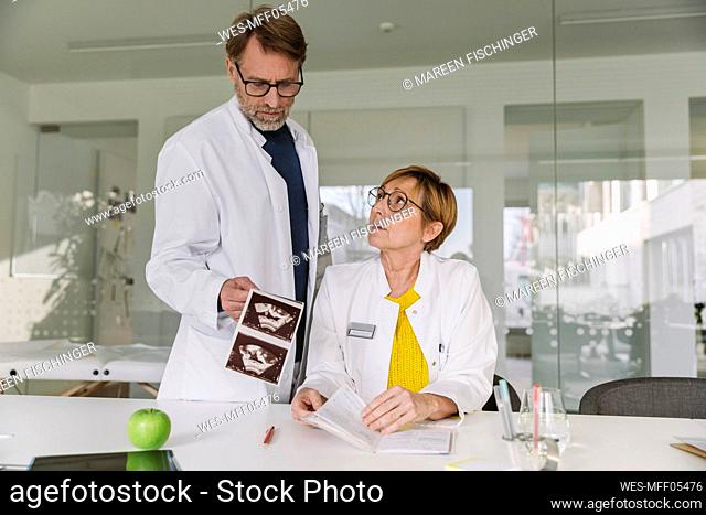 Two doctors discussing ultrasound images of fetus