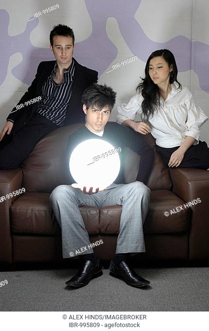 A young business man holding a brightly glowing globe with his colleagues looking