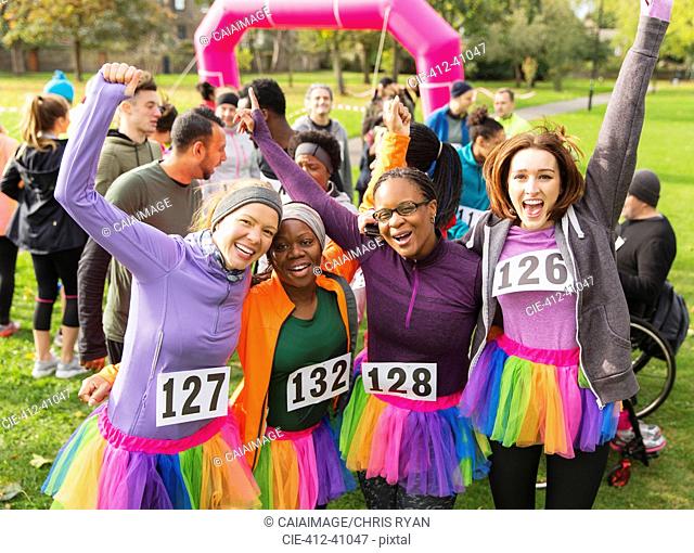 Portrait enthusiastic female runners in tutus cheering at charity run in park