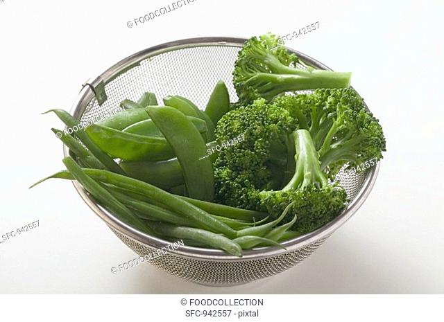Cooked beans, mangetout and broccoli in a sieve