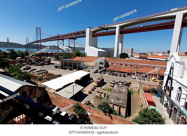 VIEW OF THE TAGUS AND THE APRIL 25TH BRIDGE, PARKING AND TRAMWAY FOR THE LX FACTORY, A FORMER INDUSTRIAL WASTELAND CONVERTED INTO A CO-WORKING SPACE, WORKSHOPS