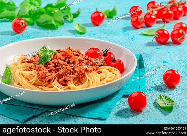 Traditional spaghetti bolognese pasta is served with fresh basil and caramelized tomatoes