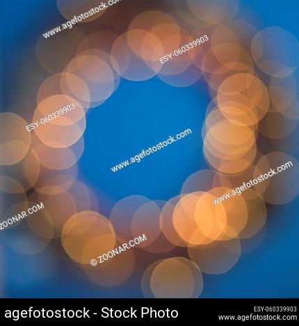 Christmas wreath of glowing bokeh lights garland on blue background top view flat lay copy space text