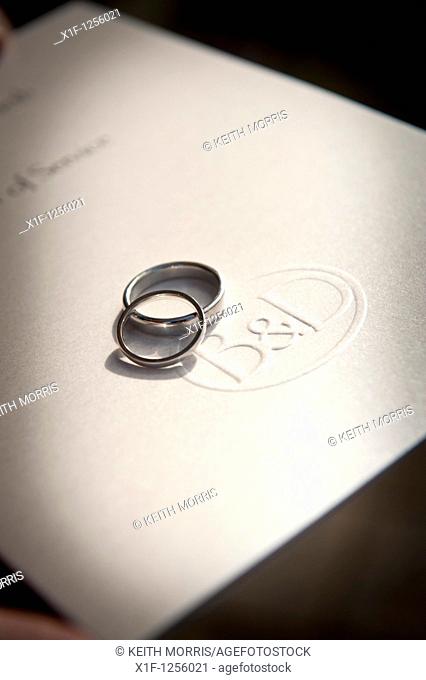 intertwined wedding rings on a copy of the order of marriage service , UK