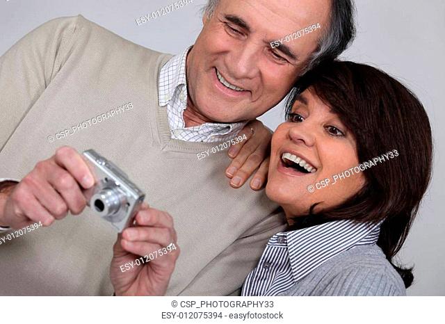 mature couple taking a picture of themselves with compact digital camera