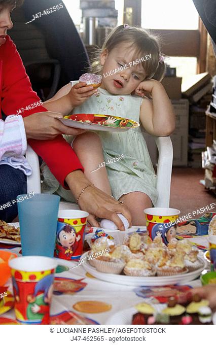 Little girl's third birthday party, a little girl looking fed up at the sight of all the food