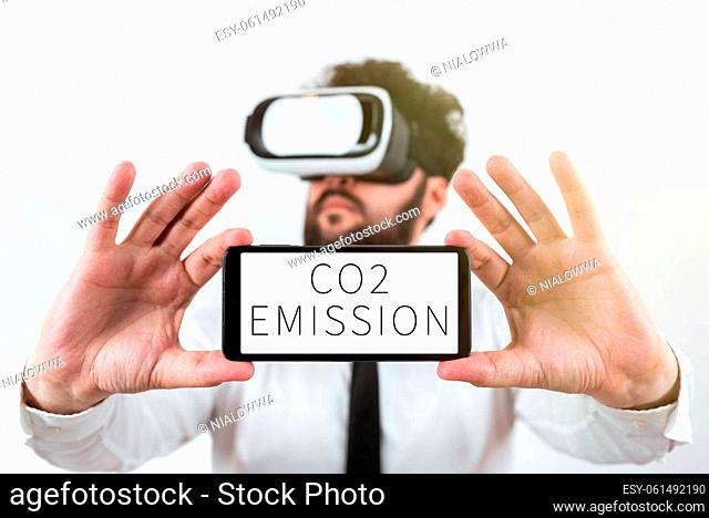 Conceptual caption Co2 Emission, Word for Releasing of greenhouse gases into the atmosphere over time Man Holding Mobile Phone With Important Messages And...
