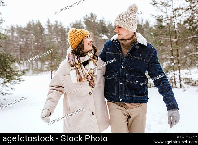 happy smiling couple walking in winter forest