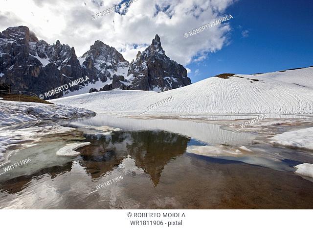 Snow is thawing leaving some puddles at the foot of the Pale di San Martino by San Martino di Castrozza, Dolomites, Trentino, Italy, Europe