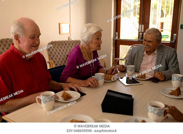 Front view of happy group of senior friends having breakfast on dining table