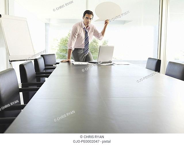 Man in boardroom with word balloon and laptop
