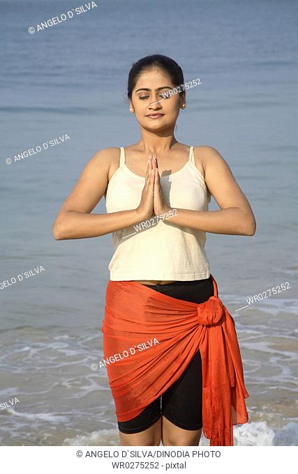 South Asian Indian young lady doing aerobics on seashore , Shiroda , Dist Sindhudurga , Maharashtra , India MR703E