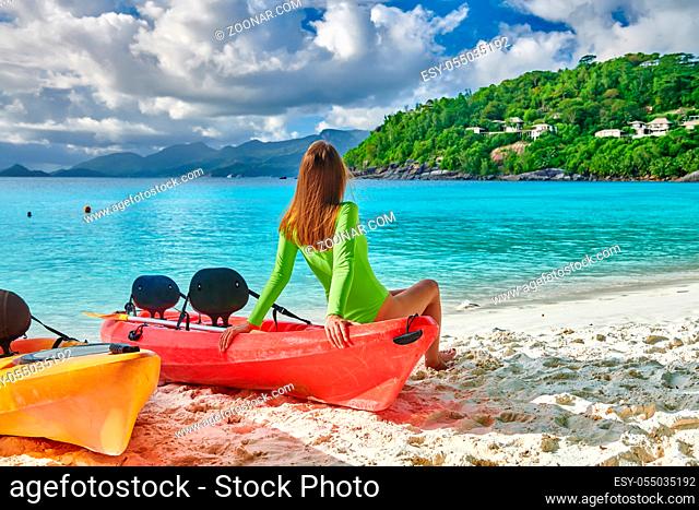 Woman sitting on kayak. Beautiful Petite Anse beach with palm tree at Seychelles, Mahe