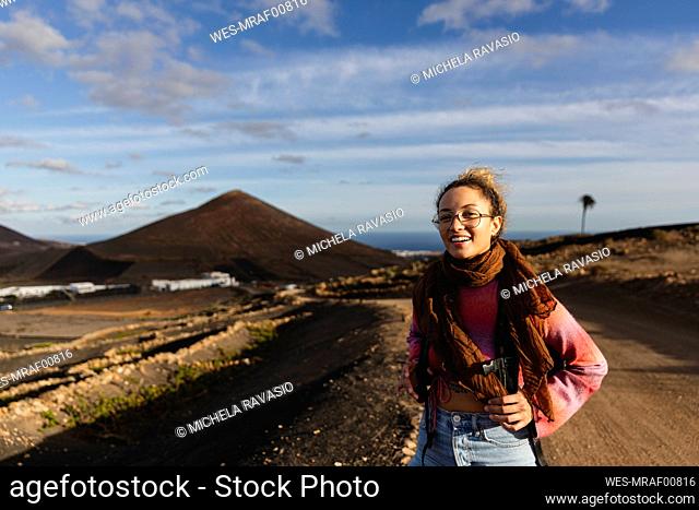 Smiling young woman with scarf on dirt road