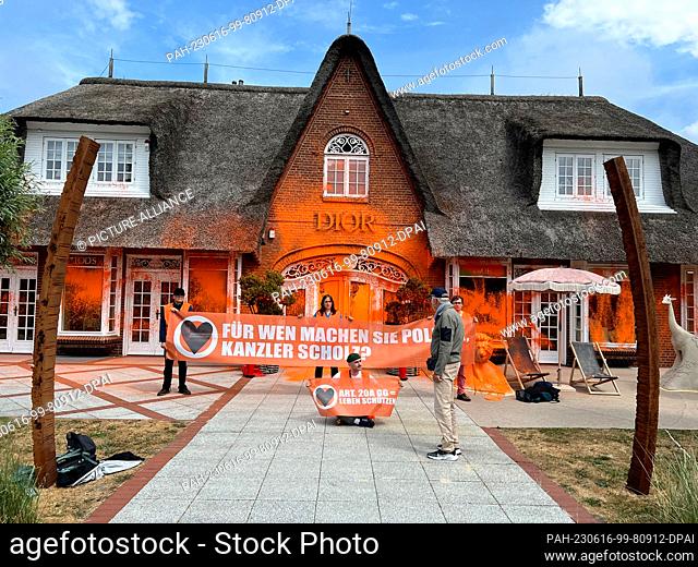 16 June 2023, Sylt: Climate activists have placed themselves in front of a spray-painted luxury store on the island of Sylt