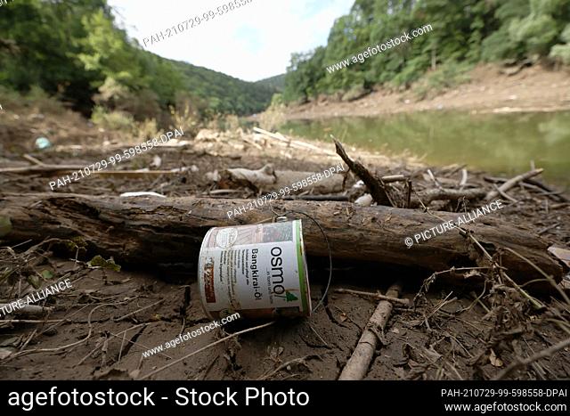 29 July 2021, North Rhine-Westphalia, Gemünd: A washed-up oil can lies on the shore of a branch of Lake Urft in the Eifel National Park