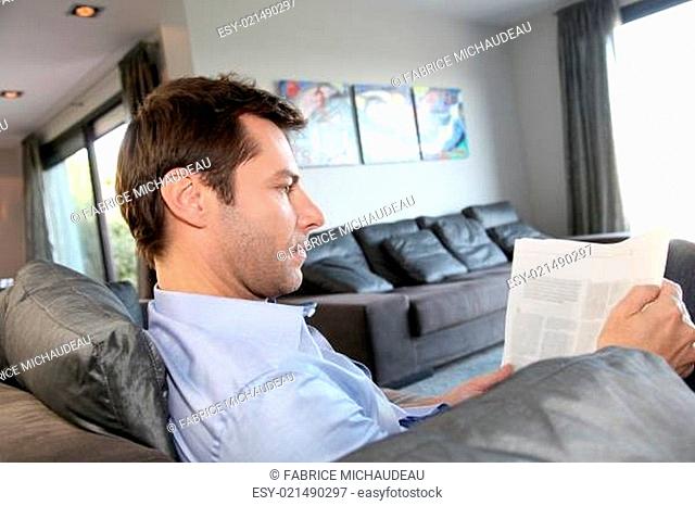 Man relaxing in sofa with newspaper