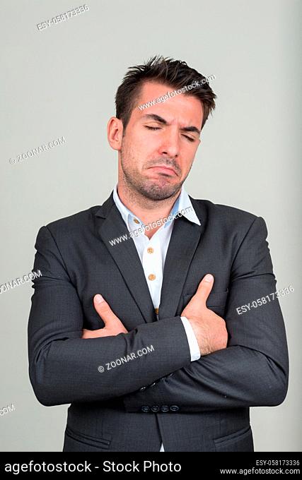 Studio shot of young handsome Hispanic businessman in suit against white background
