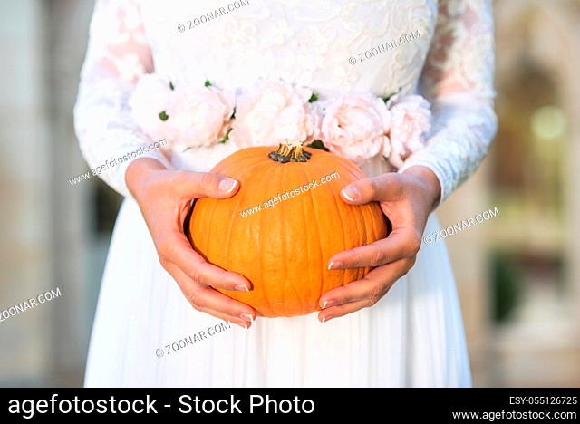 Bride holding pumpkin in her hands