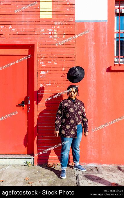 Woman standing in front of red building during sunny day