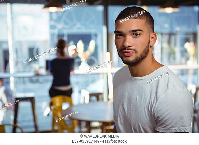 Portrait of man with friend in background at cafe