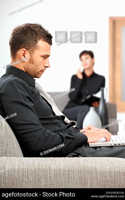 Young businessman sitting at office lobby working with laptop computer