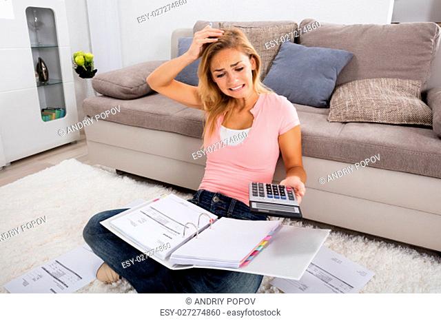Young Frustrated Woman Looking At Calculator While Calculating Invoice