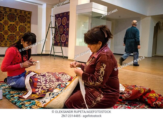 Museum workers line suzani, traditional Uzbek embroidery textile, for exhibition in new building of Samarkand State Memorial Museum, Samarkand, Uzbekistan