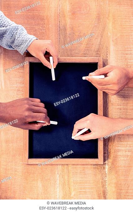 Cropped hands of business people writing on slate