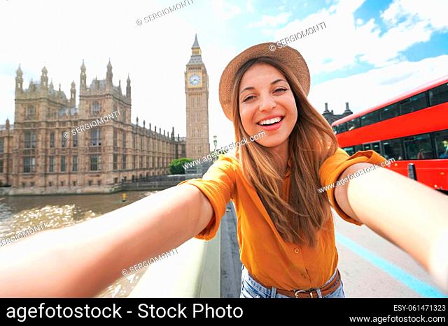 Smiling tourist girl taking self portrait in London, UK. Selfie photo of happy woman traveling in London with Big Ben tower