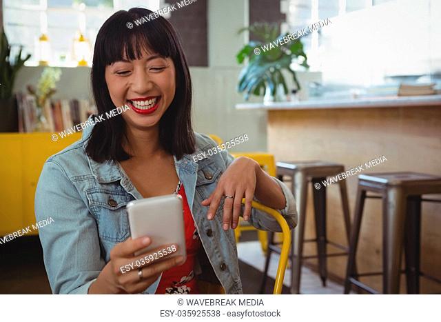 Happy woman using phone at cafe