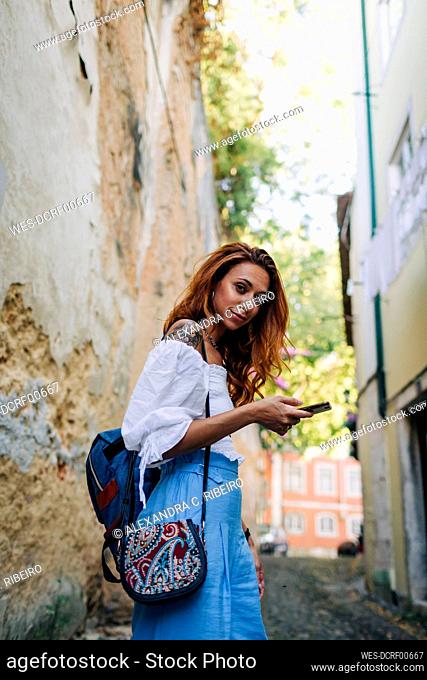 Young beautiful woman using phone while exploring town at Alfama, Lisbon, Portugal