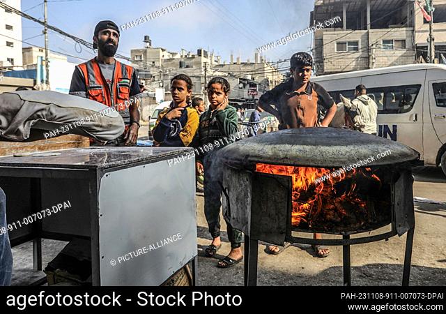 08 November 2023, Palestinian Territories, Rafah: A Palestinian baker uses firewood to bake traditional Saj bread due to the lack of cooking gas as the result...