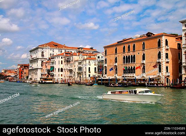 View of Grand Canal with houses and motorboats in Venice, Italy. Venice is situated across a group of 117 small islands that are separated by canals and linked...
