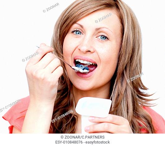 Lively woman eating a yogurt against a white background