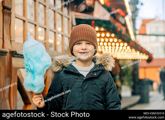 Happy boy with cotton candy standing at Christmas market