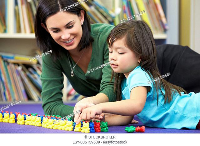 Elementary Pupil Counting With Teacher In Classroom