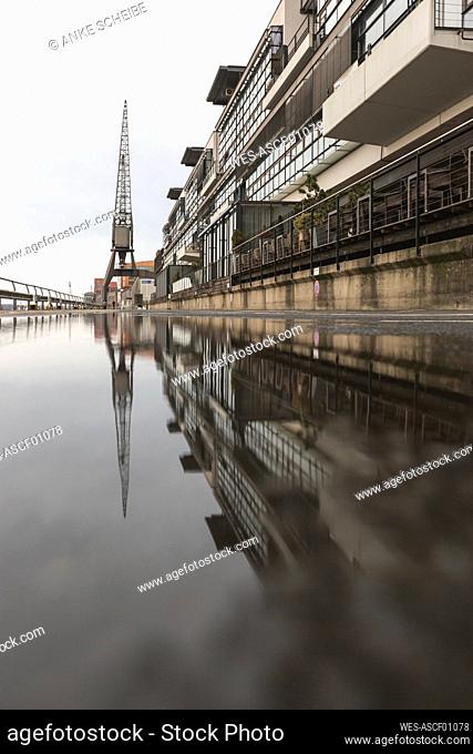 Germany, Hamburg, ¶ÿHarbor building reflecting in puddle of water