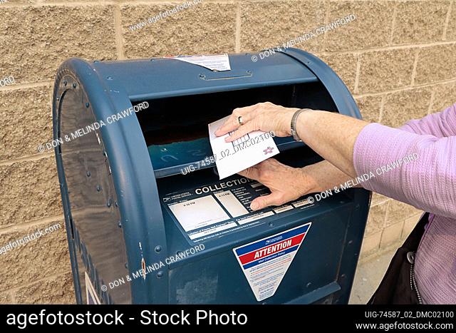 Letter being inserted into United States Postal Service blue box
