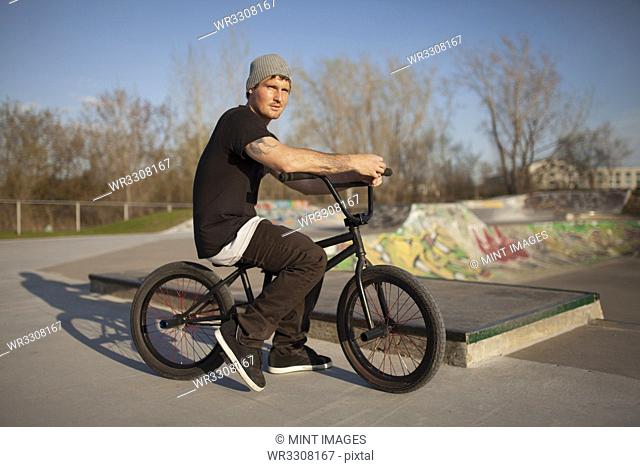 Caucasian man riding BMX bicycle at skate park